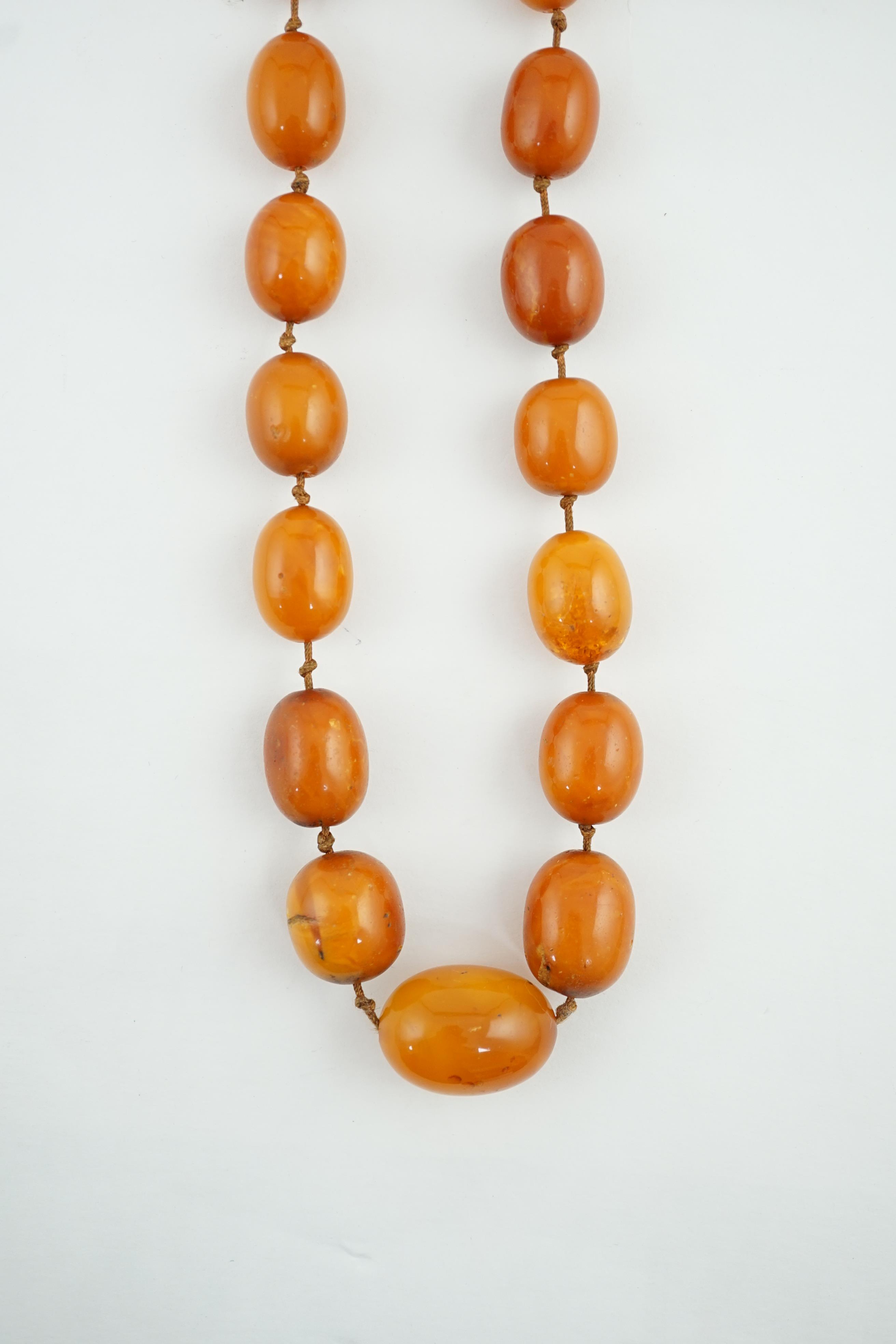 A long single strand graduated amber bead necklace